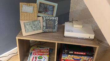En hylde med forskellige genstande, herunder et indrammet billede, en lille hvid æske og brætspil.