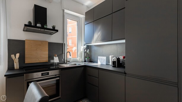Een moderne keuken met een inbouwoven, een roestvrijstalen spoelbak en een raam dat voor natuurlijk licht zorgt.