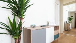Een receptiebalie met een plant, een ingelijst certificaat en een tafeltje met een boek en een decoratief object.