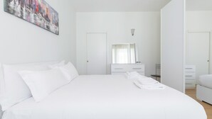 Une chambre d’hôtel moderne avec un grand lit, une table de chevet, un miroir et un tableau au mur.