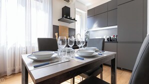 Un coin repas moderne avec une table en bois mise pour quatre personnes, comprenant des assiettes, des bols et des verres à vin.