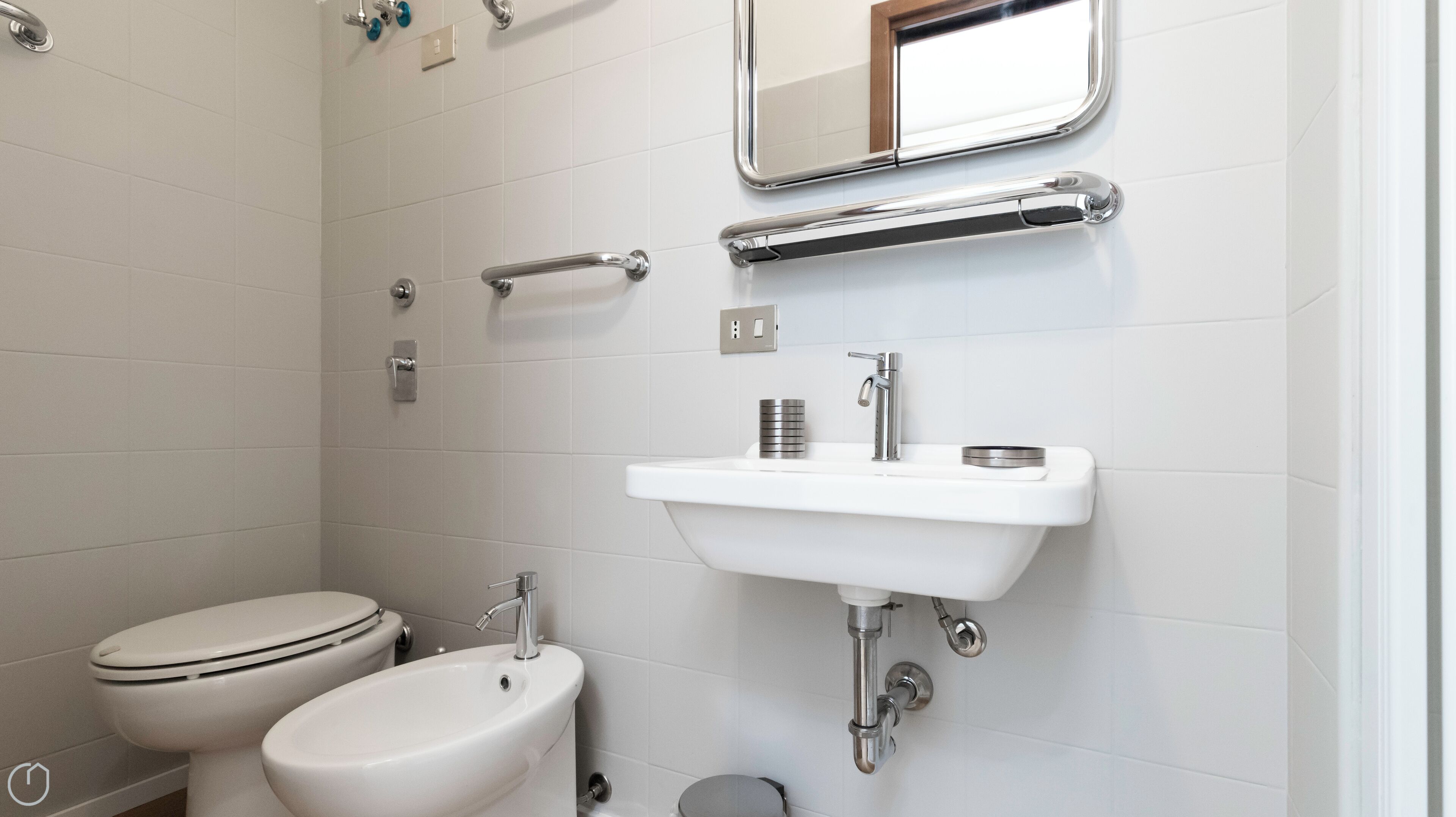 A modern bathroom with a toilet, bidet, and a sink with a mirror above.