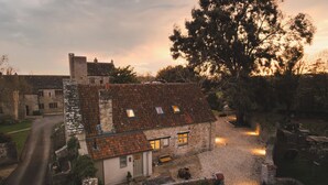 A traditional stone building with a sloped roof, a gravel driveway, and a bench.