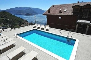 Ein rechteckiger Swimmingpool mit klarem, blauem Wasser, umgeben von Liegestühlen und einer gefliesten Terrasse.