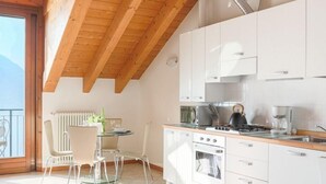 Une cuisine moderne avec des meubles blancs, une cuisinière et un coin repas comprenant une table et des chaises.