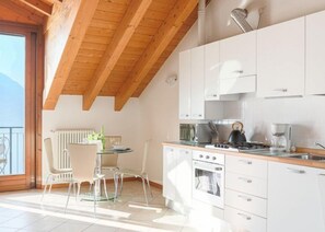 Eine moderne Küche mit weißen Schränken, einem Gasherd und einem Essbereich mit Tisch und Stühlen.