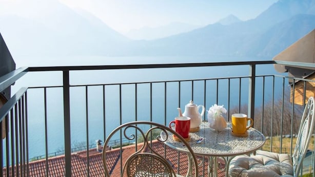 Un balcon avec une table, des chaises et une vue sur les montagnes.