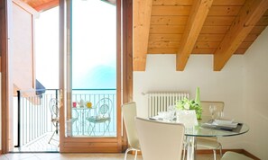 Un espace repas avec une table en verre, des chaises et une vue sur le balcon extérieur.