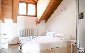 Una camera da letto con un letto, un termosifone, una finestra e travi a vista in legno.