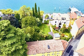 An aerial view of a coastal town with a mix of residential buildings, a green park, and a body of water. - CASA VECCHIA 3 by Design Studio (Bellano)