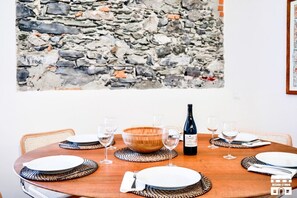 A dining table set with plates, glasses, a bottle, and a wooden bowl. - CASA VECCHIA 3 by Design Studio (Bellano)