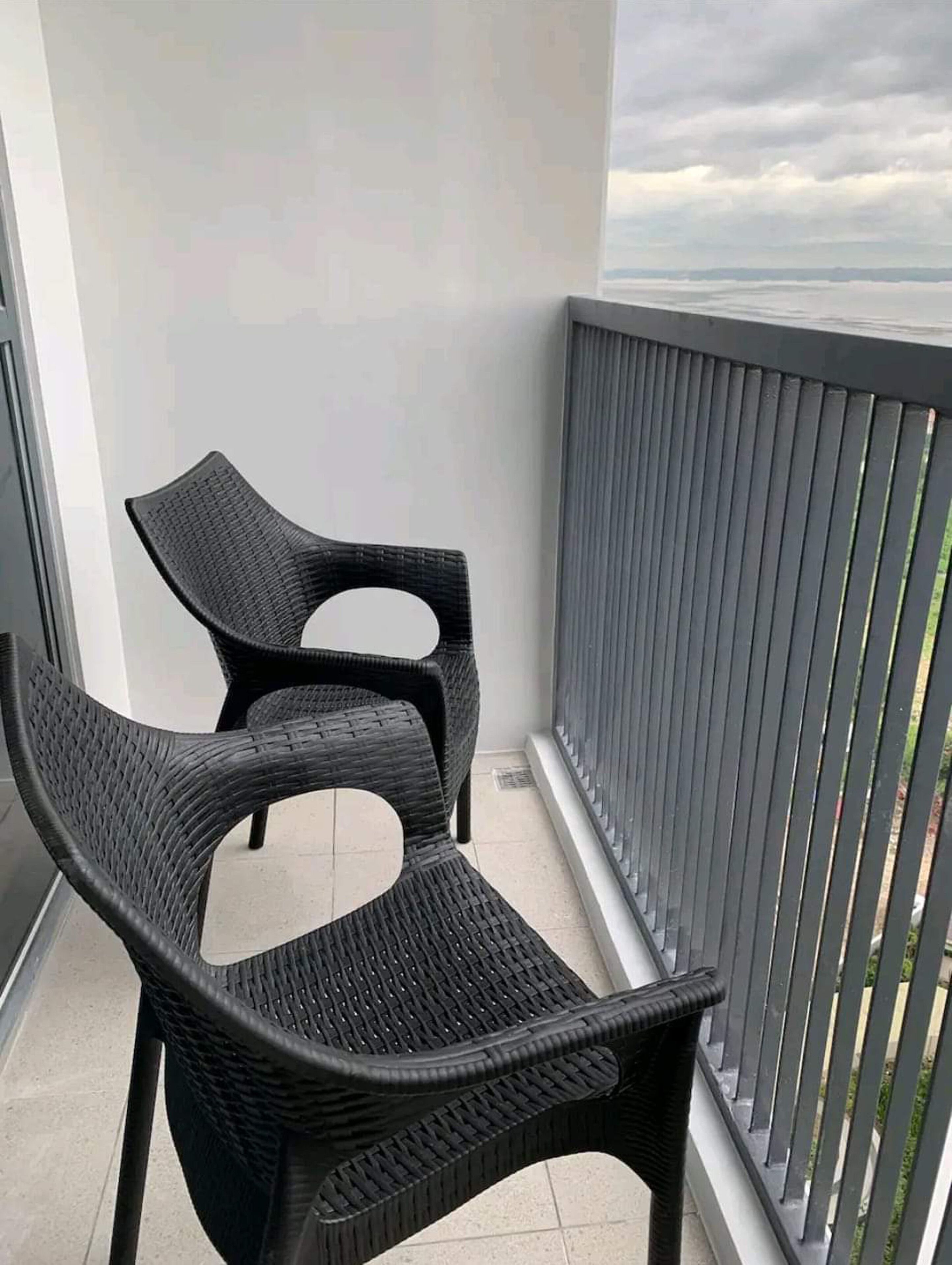 Dos sillas de mimbre en un balcón con vistas al mar.