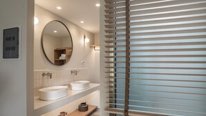 A modern bathroom with two sinks, a large mirror, and a window with blinds. - Amaryllis Hotel (Zakynthos)