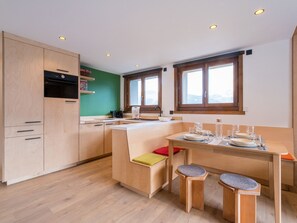 A modern kitchen with wooden cabinets, a built-in island, and a dining area with stools.