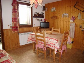 A cozy room with a wooden interior, a dining table with checkered tablecloths, and a television on a wooden stand.