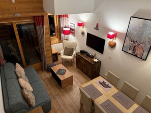 Ein gemütliches Wohnzimmer mit einer Couch, einem Couchtisch, einem Fernseher und einem Holzkasten.