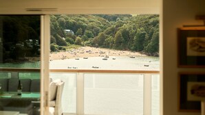 Een balkon met uitzicht op een strand, een eethoek en een ingelijste foto aan de muur.