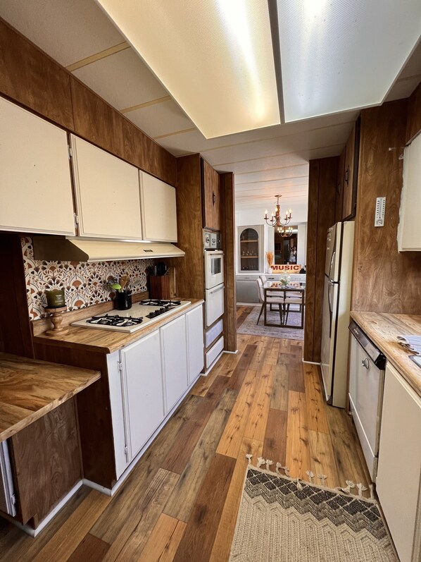 A modern kitchen with wooden cabinets, a central island, and a dining area with a chandelier. - Lakeview, boat parking, enclosed yard, pets welcome, peaceful & safe culdesac  (Lake Havasu City)