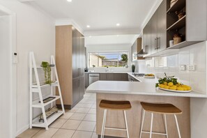 A modern kitchen with a central island, bar stools, and a view of the outside. - Rye Beach Chalet - Downstairs Only (Rye)