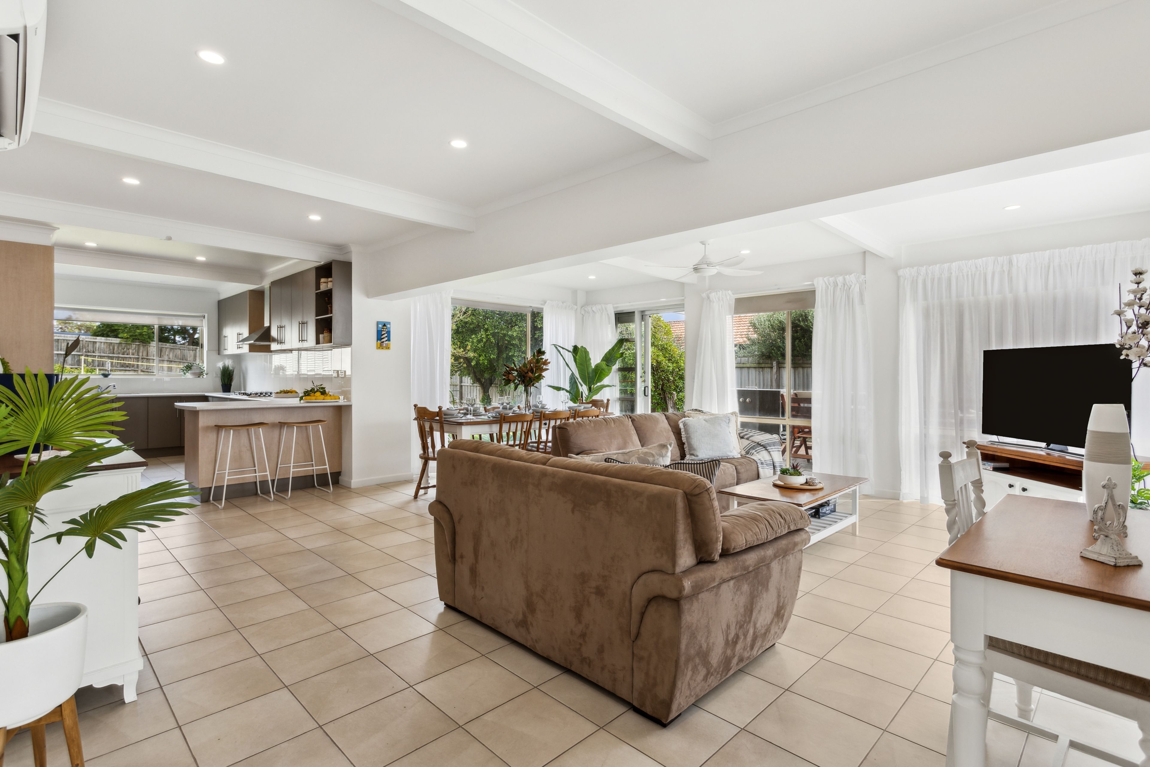 A spacious living area with a sofa, dining table, and kitchen in the background.