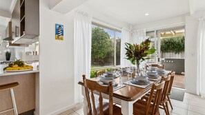 Enjoy meals in this dining area with a view of the lush garden, featuring a large window and a decorative painting on the wall.