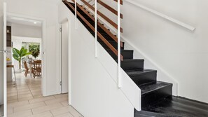 Staircase leads to an upper level with a dining area featuring a table and chairs.