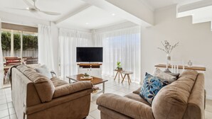 Un salon moderne doté d’un téléviseur à écran plat, de deux canapés, d’une table basse et d’une petite table d’appoint sur laquelle est posée une plante.
