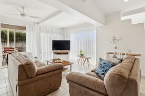 A modern living room with a flat-screen TV, two sofas, a coffee table, and a small side table with a plant. - Rye Beach Chalet - Downstairs Only (Rye)