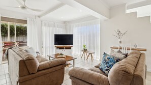 Relax in this inviting living room with a flat-screen TV, comfortable sofas, and a potted plant.