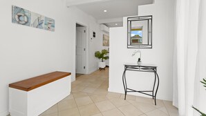 A hallway with a white bench, a small table with a potted plant, and a framed picture on the wall. - Rye Beach Chalet and Loft (Rye)