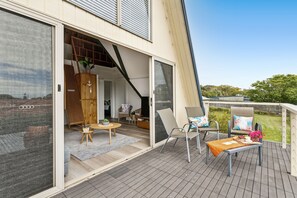 Una casa moderna con un gran ventanal que da a una sala de estar con un sofá, sillas y una mesita.