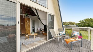 Een modern huis met een grote schuifglazen deur die leidt naar een terras.
