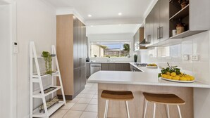 Een moderne keuken met een centraal eiland, inbouwapparatuur en uitzicht op de achtertuin.