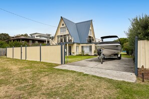 A residential property with a boat trailer in the driveway, a fenced yard, and a house with a distinctive gable roof. - Rye Beach Chalet and Loft (Rye)