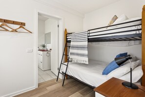 A bunk bed with a striped blanket, a bedside table with a lamp, and a wooden hanger on the wall. - Rye Beach Chalet and Loft (Rye)