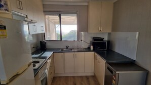 Una cocina compacta equipada con refrigerador, estufa, microondas y lavaplatos.