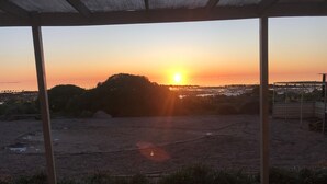 Un espacio al aire libre techado con vistas a la puesta de sol sobre una ciudad distante.