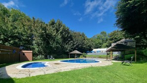 A backyard with two swimming pools, a wooden deck, and a covered seating area. - Stunning 2-bed House in Saint Columb (Newquay)