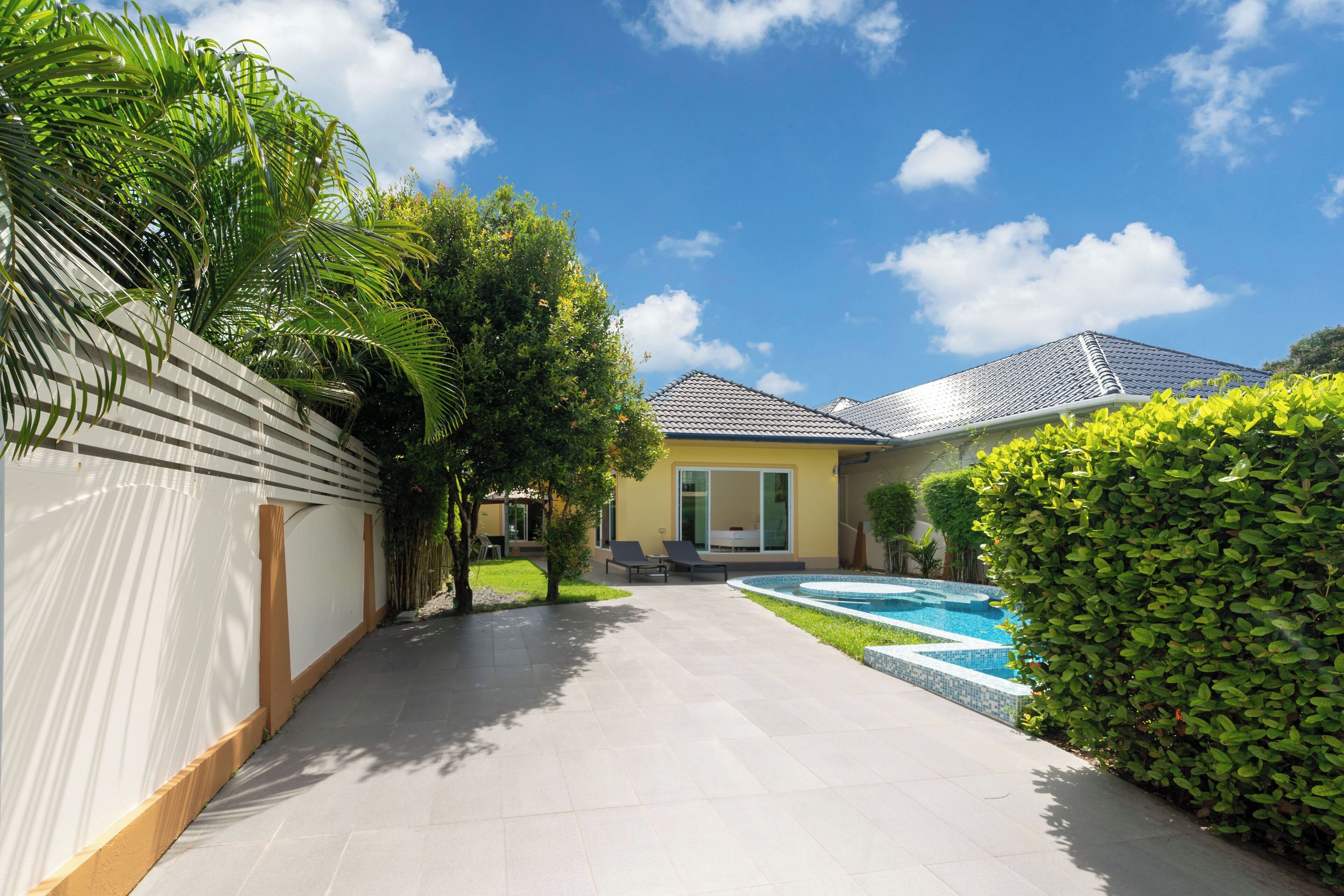 Une maison moderne dotée d’une piscine, d’un patio couvert et d’un jardin bien entretenu.
