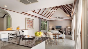 Una cocina moderna con una isla central, zona de comedor con sillas y un ventanal grande.