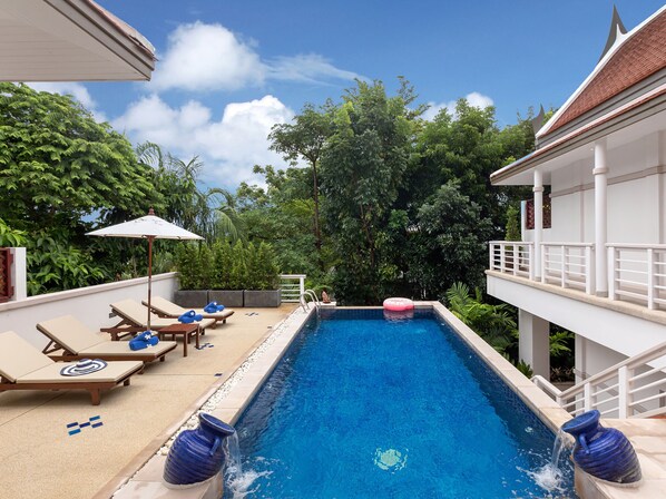 A swimming pool with lounge chairs and umbrellas, surrounded by lush greenery. - Katamanda 3 Bed Tropical Villa B3 Near Kata Beach (Karon)