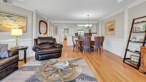 Ein geräumiges Wohnzimmer mit einem Ledersofa, einem Couchtisch mit Schiffsschrauben-Design und einem Essbereich mit Holzsesseln.