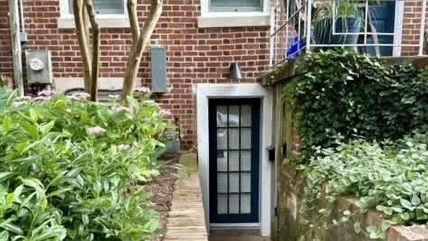A narrow brick pathway leading to a door with a window above it.