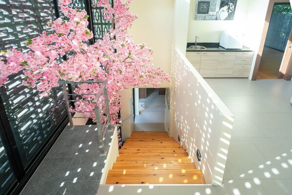 A staircase with wooden steps and a wall-mounted pink artificial tree. - Grand Villa Cedrix in the Green Paradise (Kamala)