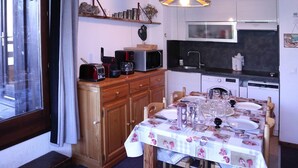 A compact kitchen with a dining table set for two, a microwave, and a sink.