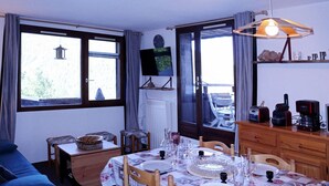 A dining area with a table set for four, a blue sofa, and a television on the wall.