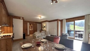 Ein Essbereich mit Holztisch, gedeckt für vier Personen, einer Couch und Blick ins Freie.