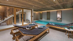 Zona d'una piscina interior moderna amb gandules de fusta, una petita piscina i una escala que condueix a un altre nivell.