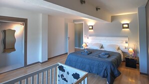 Habitación de hotel con cama, lámparas de noche, mesita de noche, espejo y vistas al exterior.