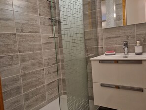A modern bathroom with a shower, a sink, and a mirror.